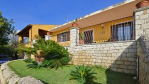A yellow building with a stone wall and a balcony with metal railings. - Villa Torres in Scicli (Scicli)