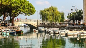 A canal with boats docked, a stone bridge, and trees. - Villa Alberti 900m From Garda Lake (Salò)
