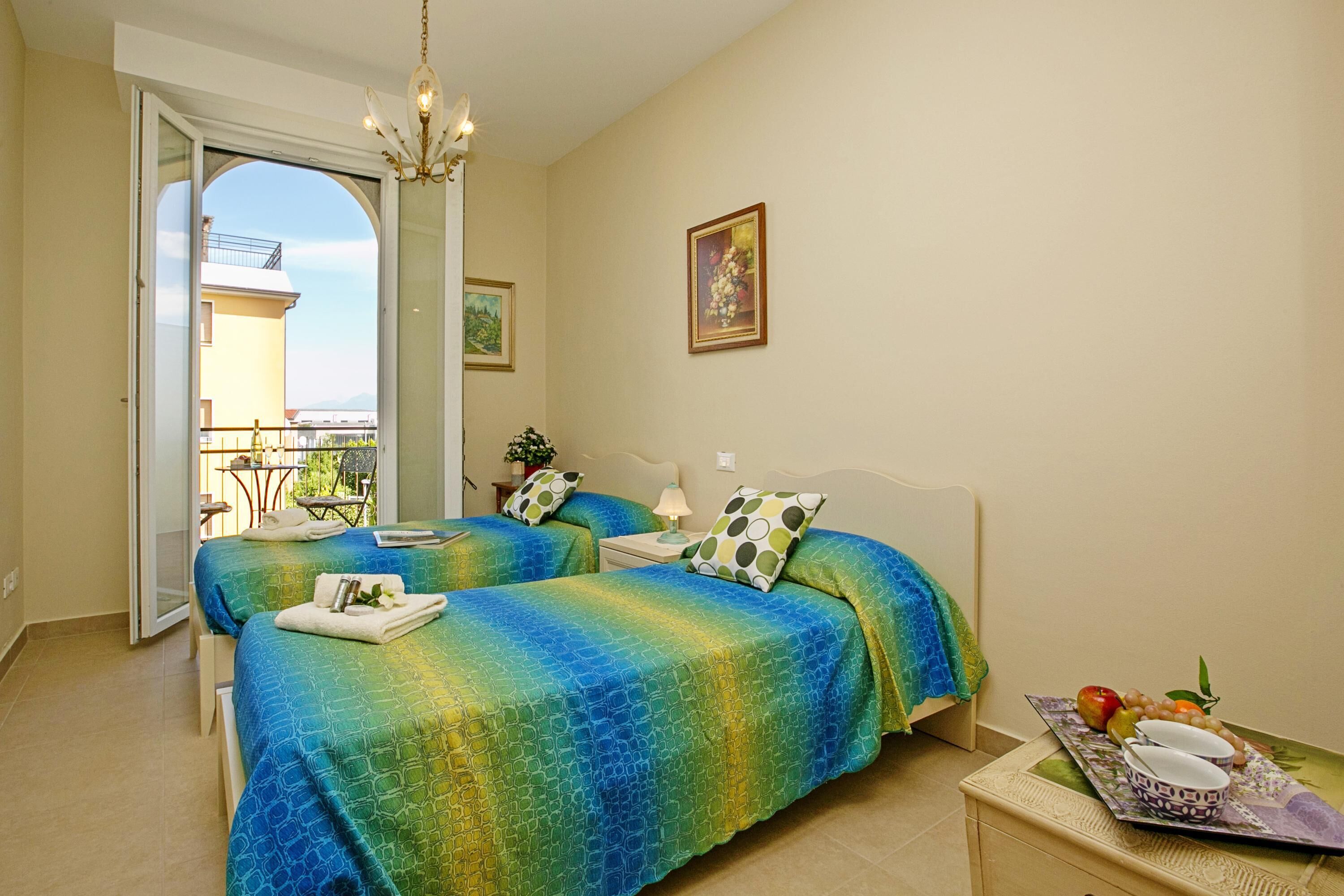 Une chambre d’hôtel avec deux lits, un balcon et une table à manger avec des fruits.