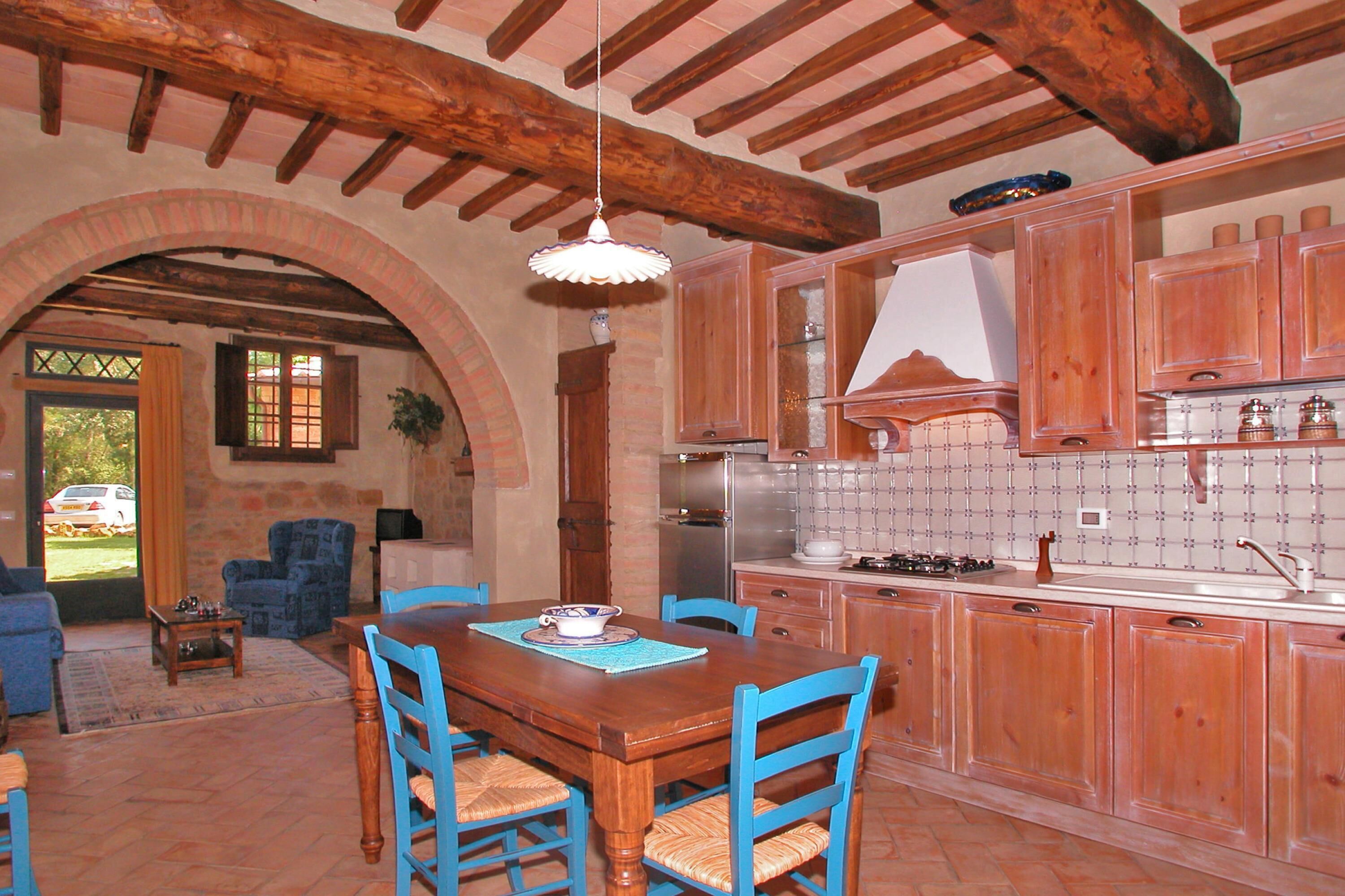 A rustic kitchen with wooden cabinets, a dining table with chairs, and a hanging light fixture.