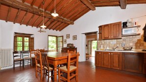 A spacious kitchen with wooden cabinets, a dining table with chairs, and a tiled backsplash. - Molino del Ponte in Radda in Chianti (Radda in Chianti)