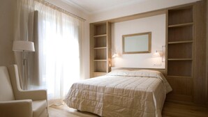 Una camera da letto con un letto, una sedia, una lampada e scaffali a muro.
