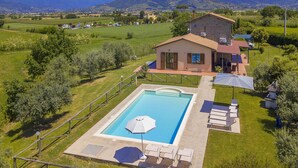 A house with a swimming pool, outdoor furniture, and a view of the countryside.