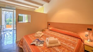 A bedroom with a bed, a bedside table, a lamp, and a window. - Yellow Apartment Desenzano With Smart TV (Desenzano del Garda)