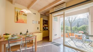 A dining area with a wooden table and chairs, a yellow cabinet, and a painting on the wall. - Yellow Apartment Desenzano With Smart TV (Desenzano del Garda)