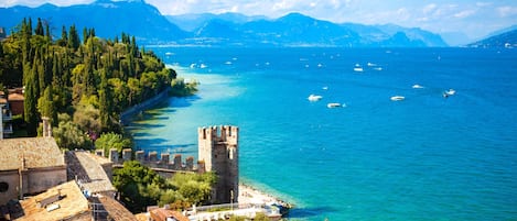 A coastal town with historic architecture, a tower, and clear blue waters.