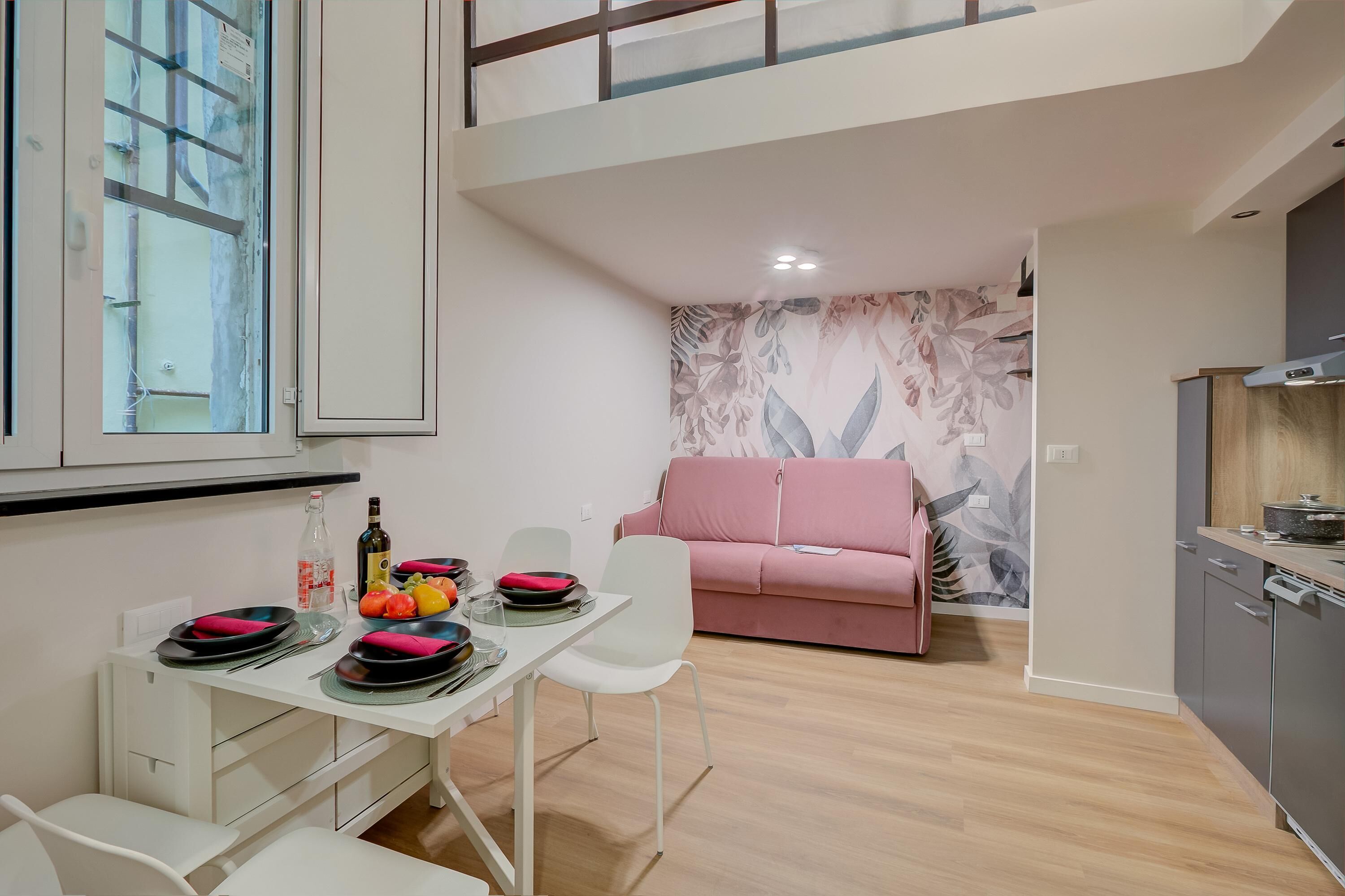 A modern apartment with a dining area, a pink sofa, and a kitchen.