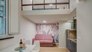 Egy modern apartman, étkezővel, rózsaszín kanapéval és kis konyhasarokkal.