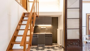 A kitchen with a built-in dishwasher, a wooden staircase, and a tiled floor. - Nobel Flat - Historic Center (Genoa)