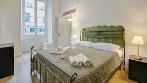 A neatly made bed with rolled towels, a bedside lamp, and a view of the outside through a window. - Royal - Historic Center (Genoa)