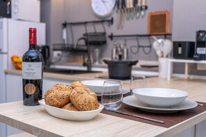 Un comptoir de cuisine avec une bouteille de vin, un panier de pain et un verre.