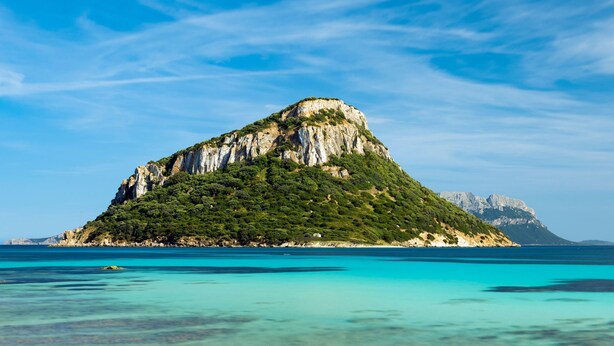 Een kustlandschap met een groot rotsachtig eiland en helder turquoise water.