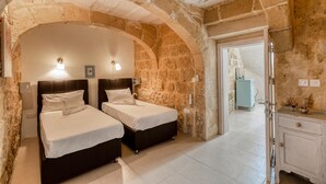 A bedroom with two beds, stone walls, and a wooden cabinet. - Ta Patee Pool Farmhouse in Gozo (San Lawrenz)