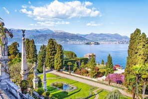 A formal garden with statues, a pond, and a view of a lake and mountains. - Residenza Il Parco Family Retreat (Ispra)