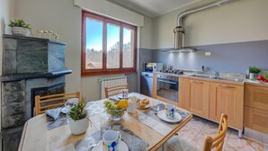 A modern kitchen with a dining area, a fireplace, and a large window.