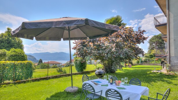 An outdoor dining area with a table set for two, an umbrella, and a view of the countryside.
