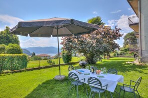 An outdoor dining area with a table set for two, an umbrella, and a view of the countryside. - Residenza Il Parco Family Retreat (Ispra)