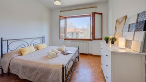 A bedroom with a bed, a dresser, a window, and a radiator.