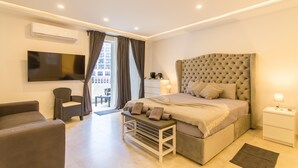 A modern bedroom with a large bed, a TV mounted on the wall, a bedside table with a lamp, and a window with curtains. - Top Modern Prime Location 2mn to the sea (St. Paul's Bay)