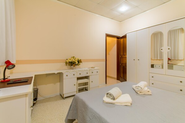 Ein Schlafzimmer mit Bett, Schreibtisch, Spiegel und Kleiderschrank.