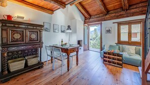 Ein geräumiges Zimmer mit Holzdielen und hohen Decken, ausgestattet mit einem Esstisch mit Stühlen, einer Couch und einem Kamin.