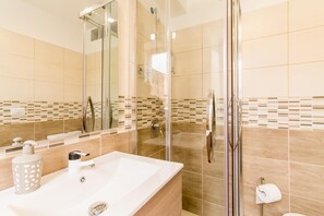 A modern bathroom with a glass-enclosed shower, a large sink, and a mirror.