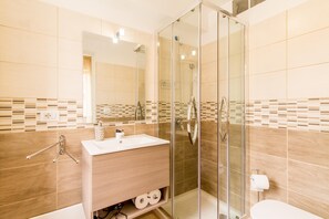 A modern bathroom with a glass-enclosed shower, a wooden vanity with a sink, and a toilet.