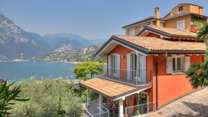 Ein Haus am Ufer mit einem Balkon mit Blick auf einen See und Berge.