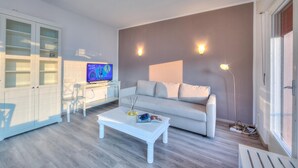 A modern living room with a white sofa, a white coffee table, and a television on a white cabinet. - Villa Panorama With Private Pool (Nago-Torbole)