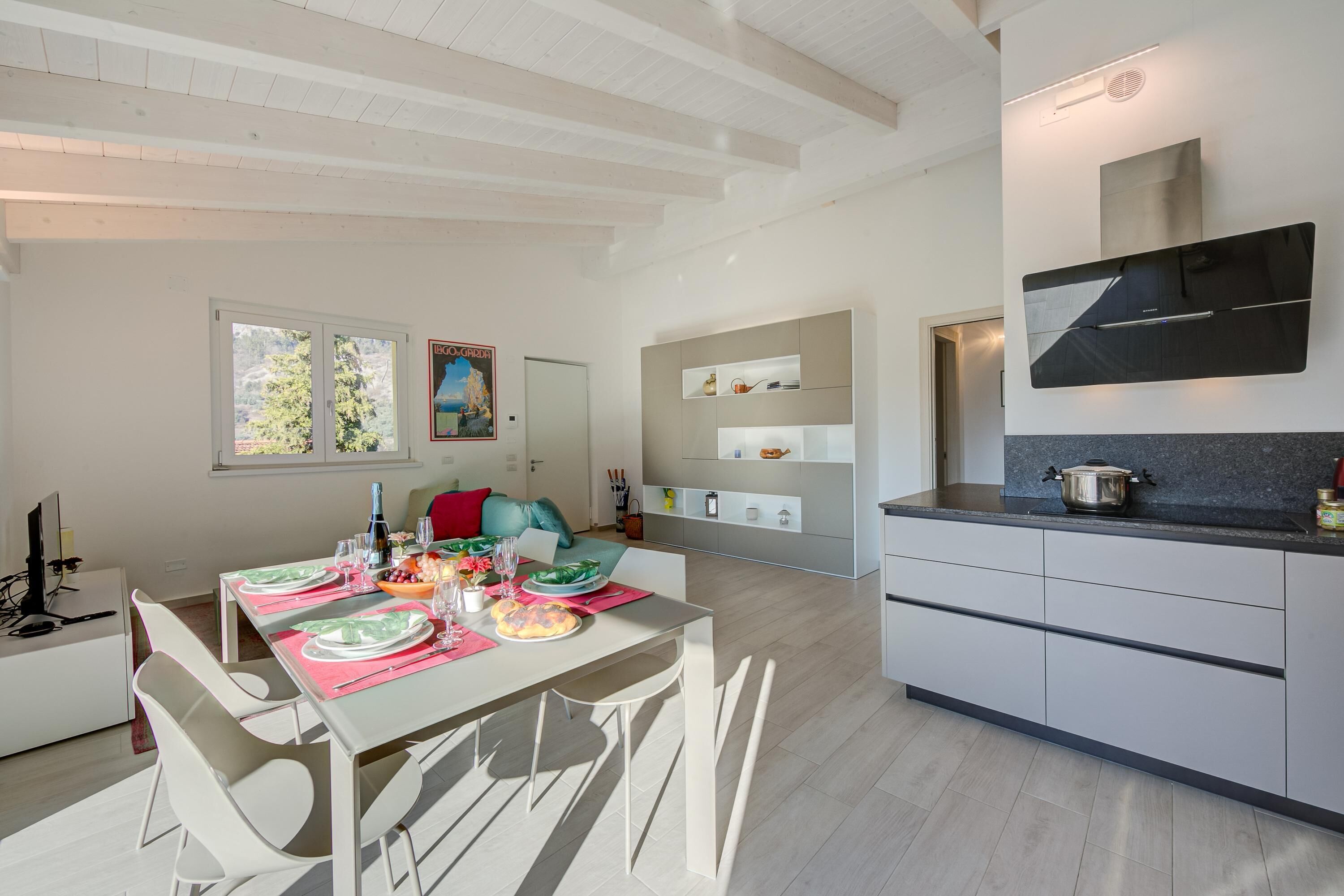 Une cuisine moderne dotée d’une cuisinière intégrée, de meubles blancs et d’un coin repas avec une table dressée pour quatre personnes.