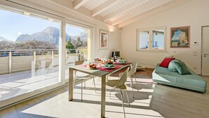 Een ruime woonkamer met balkon, een eettafel gedekt met borden en glazen, en een groene bank.