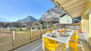 Een balkon met een eettafel, met uitzicht op een bergachtig landschap.