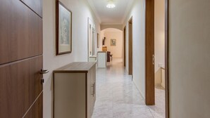 A hallway with wooden doors, framed artwork, and a tiled floor. - Merill Pool and Sea Charming Apart 2 (Mellieha)