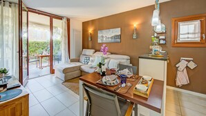 A modern living room with a sofa, dining table, and a view of the garden through glass doors. - The Peace Of The Lake (Arco)