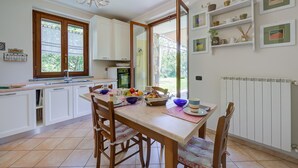 Une cuisine avec une table à manger, des chaises et une vue sur l’extérieur.
