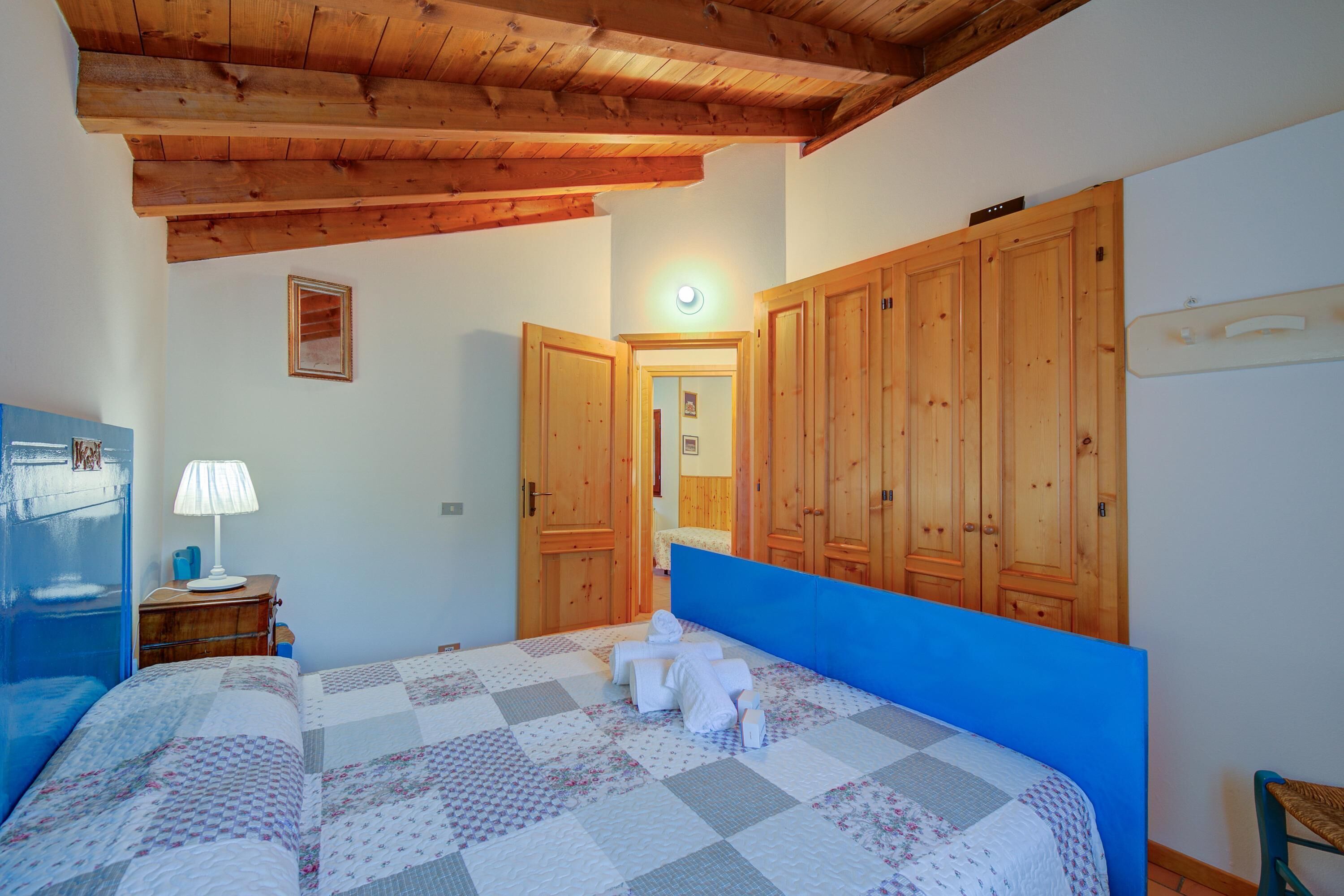 Un dormitorio con cama, armario de madera y mesita de noche con lámpara.