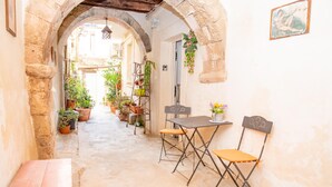A narrow alleyway with a table and chairs, potted plants, and a bench. - Nike Home 200m From Sea (Syracuse)