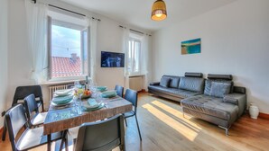 A modern living room with a dining area, a grey sofa, and a TV on the wall. - Muri Di Arco in Arco (Arco)