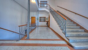 A spacious hallway with a marble floor, a staircase with metal railings, and a door at the end. - Muri Di Arco in Arco (Arco)