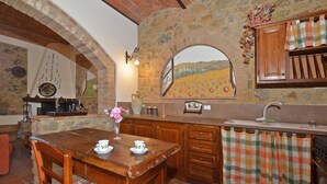 A rustic kitchen with a wooden table, chairs, and a stone wall. - Pozzovecchio in Casole d Elsa (Casole d'Elsa)