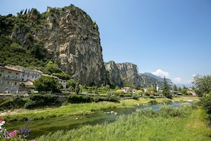 A river with a rocky cliff and buildings along the riverbank. - Star Apartment in Arco (Arco)