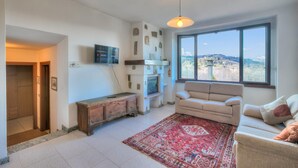 Un salon avec un canapé, un tapis rouge à motifs, un téléviseur et un mur en pierre.
