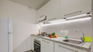 A modern kitchen with a built-in oven, a stainless steel sink, and a gas stove. - Zio Enry Garden Orta Lake (Armeno)