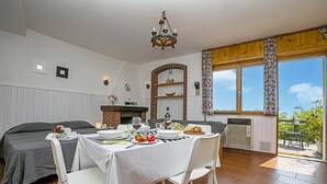 A dining area with a table set for two, a brick fireplace, and a view of the outdoors. - Tremosine Wonderful Lake View 1 (Tremosine)