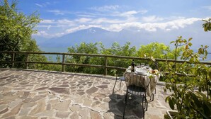 A stone patio with a table set for two, overlooking a mountainous landscape. - Tremosine Wonderful Lake View 1 (Tremosine)