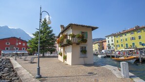 A cobblestone street with a small building, benches, and a boat docked by the water. - Tremosine Wonderful Lake View 1 (Tremosine)
