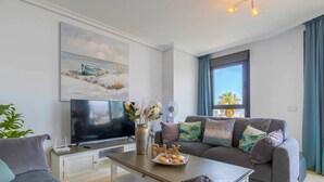 Un soggiorno moderno con una TV a schermo piatto, un divano, un tavolino da caffè e un quadro appeso al muro.