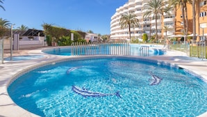 Una piscina con bordo decorativo, circondata da una recinzione e palme.