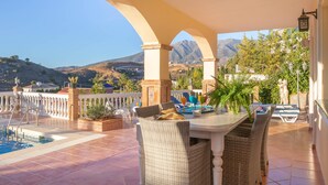 A covered outdoor patio with a pool, wicker chairs, and a table with drinks. - Villa Carlos Mijas Golf (Mijas)