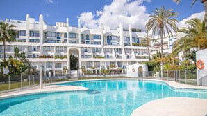 A modern hotel with a pool area, featuring a multi-story building with balconies and a clear blue sky. - Marbella Pool House Ph24 on sea Shore (Marbella)
